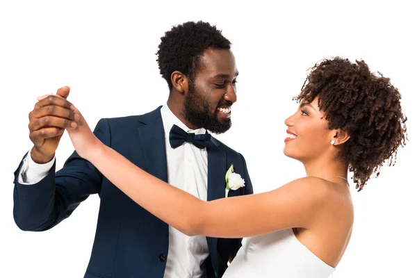 Beau marié afro-américain regardant mariée heureuse tout en tenant les mains isolées sur blanc — Photo de stock