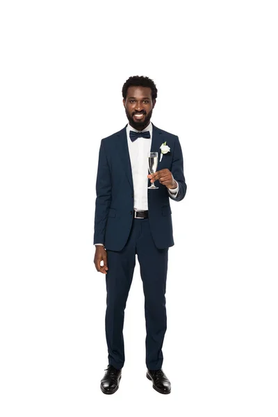 Happy african american bridegroom holding champagne glass and standing isolated on white — Stock Photo