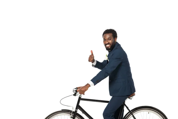 Щасливий афроамериканський наречений їде на велосипеді і показує великий палець вгору ізольовано на білому — стокове фото