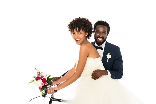 Heureux marié afro-américain près de mariée attrayante vélo d'équitation isolé sur blanc — Photo de stock