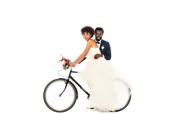 Heureux marié afro-américain près de mariée gaie vélo d'équitation isolé sur blanc — Photo de stock