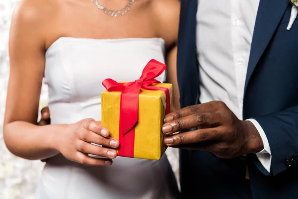 Cropped view of african american man giving present to bride — Stock Photo