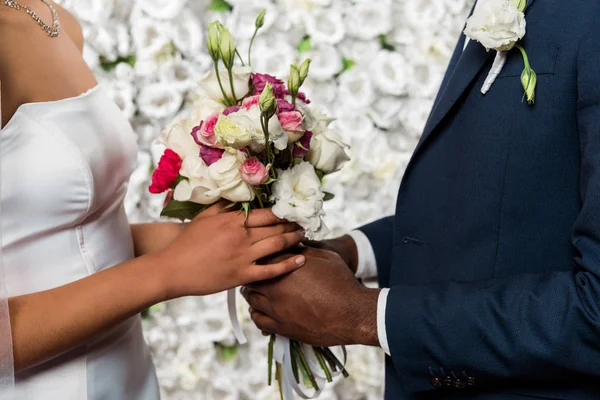 Vue recadrée du marié afro-américain et de la mariée tenant des fleurs — Photo de stock