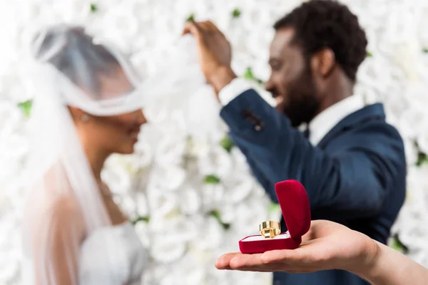 Corte vista de homem segurando caixa com anel de casamento perto de casal afro-americano — Fotografia de Stock