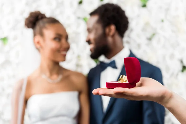 Selective focus of man holding box with wedding ring near african american couple — Stock Photo