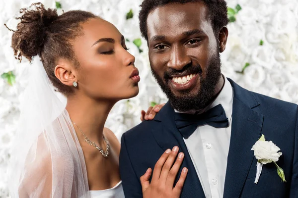 Mariée afro-américaine en voile avec visage de canard près marié heureux et fleurs — Photo de stock