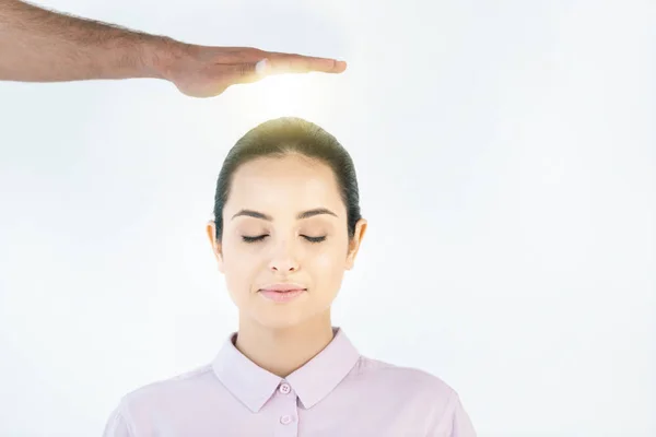 Cropped view of healer putting hand above head of attractive woman with closed eyes on white — Stock Photo