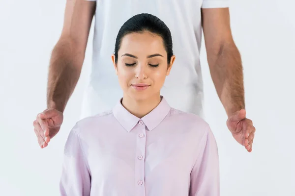 Visão cortada de curandeiro colocando as mãos perto de mulher atraente com os olhos fechados isolados no branco — Fotografia de Stock