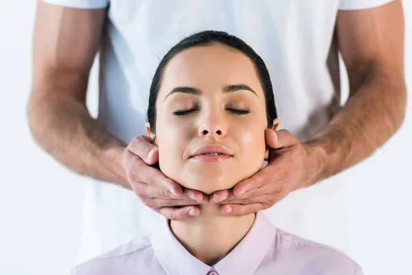 Обрізаний вид масажиста тримає руки на шиї привабливої жінки ізольовані на білому — стокове фото