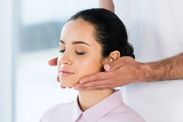 Обрізаний вид масажиста тримає руки біля шиї привабливої жінки — стокове фото
