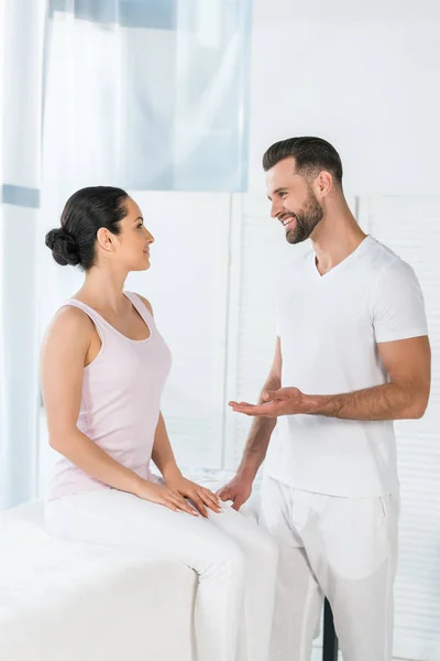 Massagista alegre gesto enquanto olha para mulher atraente — Fotografia de Stock