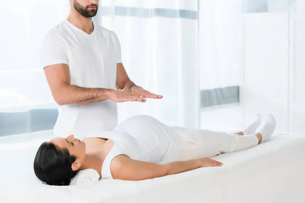 Homem barbudo cura morena grávida deitada na mesa de massagem — Fotografia de Stock