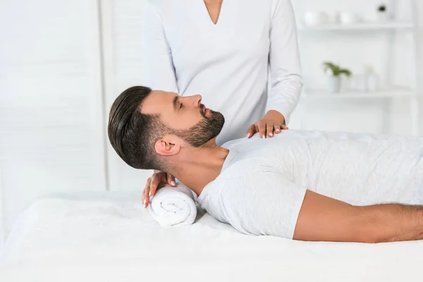 Cropped view of healer standing near handsome man in spa center — Stock Photo