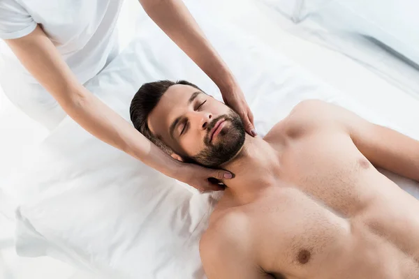Vue recadrée de masseur faisant massage du cou à bel homme avec les yeux fermés — Photo de stock