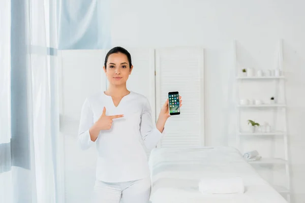 UKRAINE, KYIV - MAY 20, 2019: attractive woman pointing with finger at iphone — Stock Photo