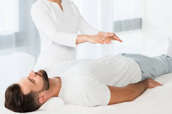 Cropped view of woman putting hands above body while healing handsome man — Stock Photo