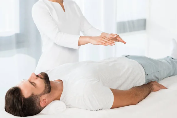 Recortado vista de la mujer poniendo las manos por encima del cuerpo mientras curación hombre guapo - foto de stock