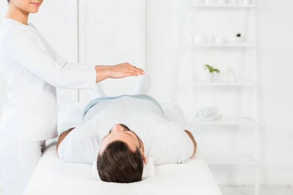 Cropped view of cheerful woman putting hands above body while healing handsome man — Stock Photo