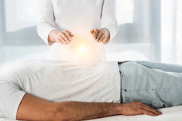 Vue recadrée de la femme mettant les mains au-dessus du corps tout en guérissant l'homme — Photo de stock