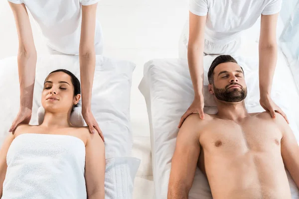 Top view of masseurs doing massage to man and woman with closed eyes in spa center — Stock Photo