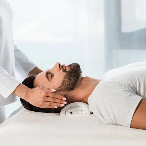 Ausgeschnittene Ansicht einer Frau, die einen bärtigen Mann mit geschlossenen Augen heilt — Stockfoto