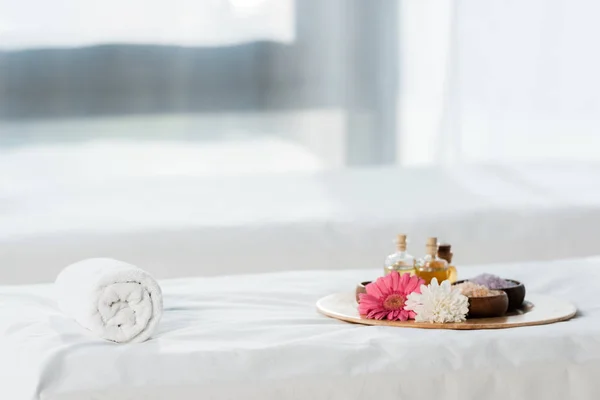 Selective focus of tray with bottles of oil, bowls with sea salt and flowers in spa center — Stock Photo