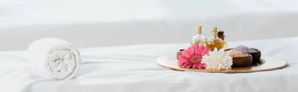 Panoramic shot of tray with bottles of oil, bowls with sea salt and flowers in spa center — Stock Photo