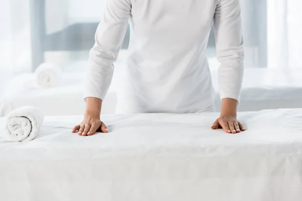 Vue recadrée du masseur debout près de la table de massage avec rouleau de serviette — Photo de stock