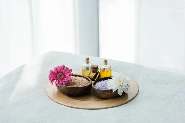 Bandeja com garrafas de óleo, tigelas de madeira com sal marinho e flores no centro de spa — Fotografia de Stock