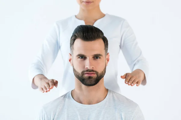 Cropped view of healer holding hands near shoulders of handsome man isolated on white — Stock Photo
