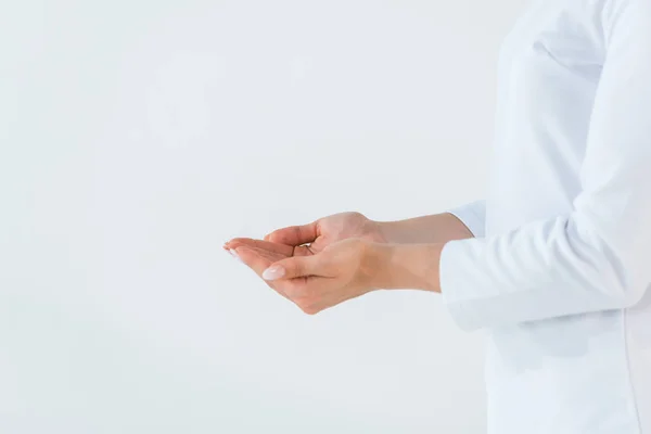 Abgeschnittene Ansicht einer Frau, die mit gestutzten Händen auf weiß isoliert steht — Stockfoto