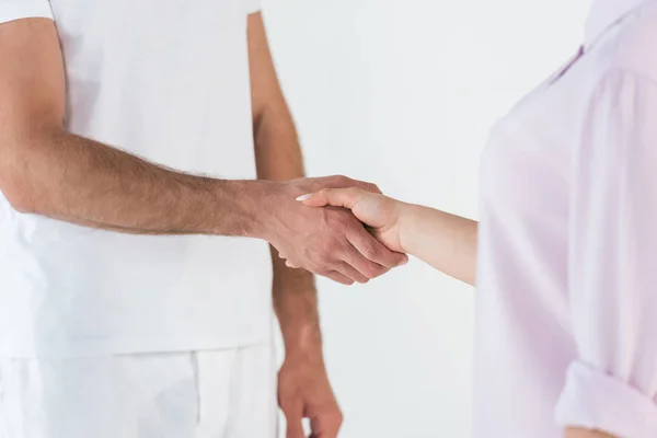 Vista ritagliata di uomo e donna che stringono le mani isolate su bianco — Foto stock