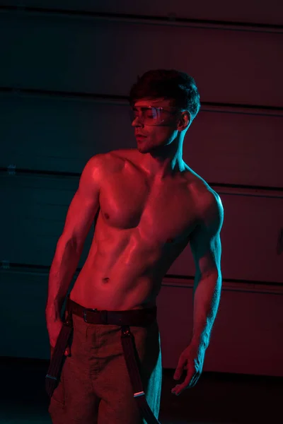 Sexy shirtless fireman in protective goggles in darkness — Stock Photo