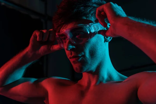 Sexy shirtless fireman in protective goggles in darkness — Stock Photo