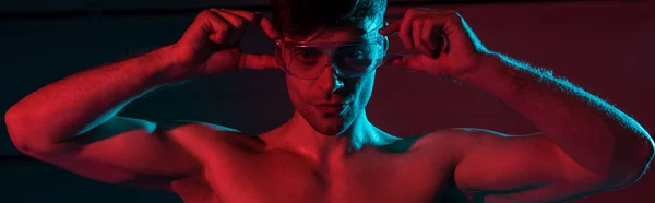 Panoramic shot of sexy shirtless fireman in protective goggles in darkness — Stock Photo
