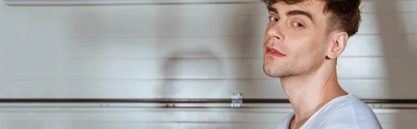 Panoramic shot of smiling man in white t-shirt looking at camera — Stock Photo