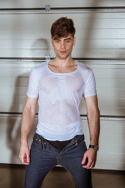 Bonito homem em jeans e molhado branco t-shirt — Fotografia de Stock