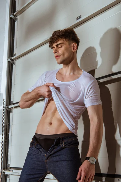 Sexy muscular homem no branco t-shirt mostrando torso — Fotografia de Stock