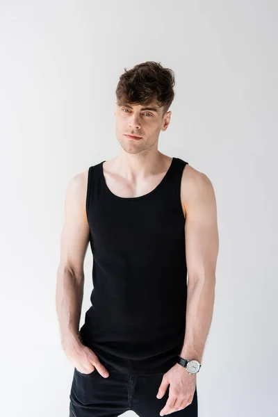 Man in black sleeveless shirt with hand in pocket isolated on grey — Stock Photo