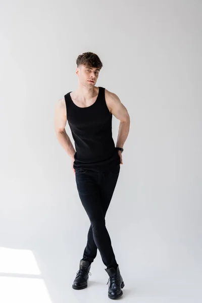 Full length view of man in sleeveless shirt standing on grey — Stock Photo