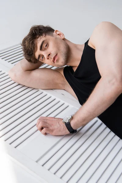 Bel homme en chemise noire sans manches couchée sur le gris — Photo de stock