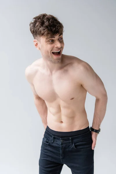 Сміється без сорочки м'язистий чоловік дивиться ізольовано на сірий — стокове фото