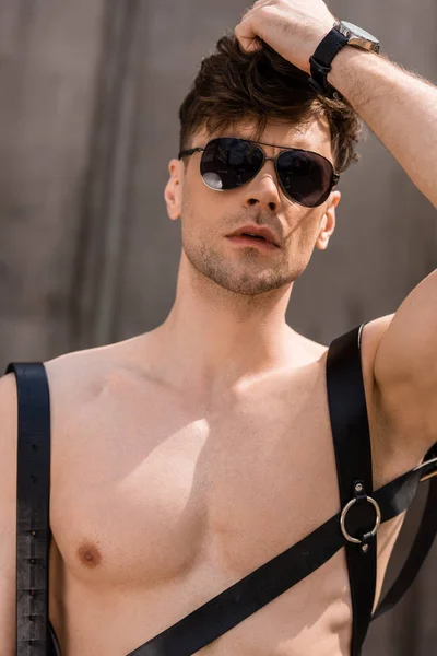 Стильний сексуальний чоловік в чорних сонцезахисних окулярах і мечовому поясі — стокове фото
