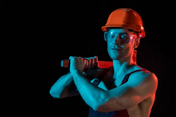 Bombero sexy en general, hardhat y gafas protectoras que sostienen el hacha de cabeza plana aislado en negro - foto de stock