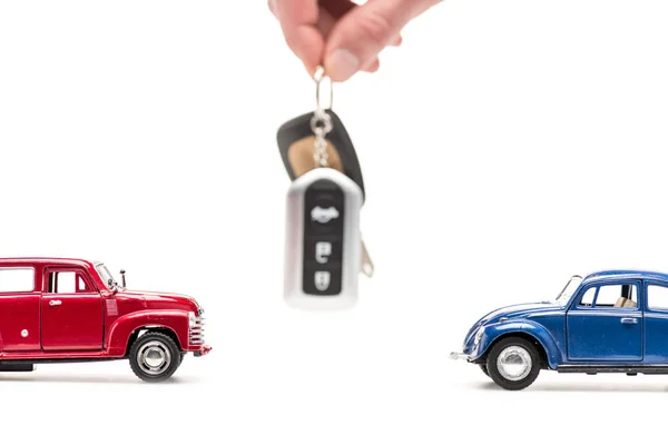 Visão cortada do homem segurando a chave perto de carros de brinquedo no branco — Fotografia de Stock