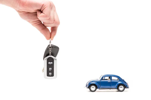 Cropped view of man holding key near toy car on white — Stock Photo