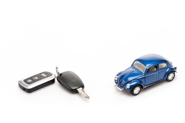 Keys and blue toy car on white surface — Stock Photo