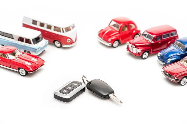 Keys and colorful toy cars on white surface — Stock Photo