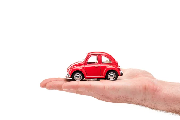 Vista recortada del hombre sosteniendo coche de juguete rojo en blanco - foto de stock