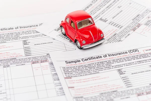 Carro de brinquedo vermelho em documentos de seguro em branco — Fotografia de Stock